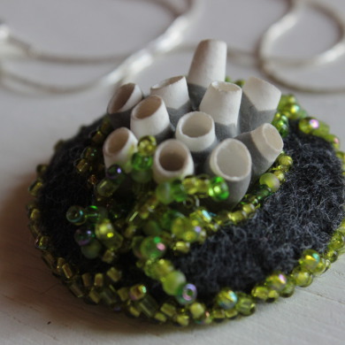 collier porcelaine blanche inspiration corail sur feutre gris, brodé de perles vertes, sur chaine en argent